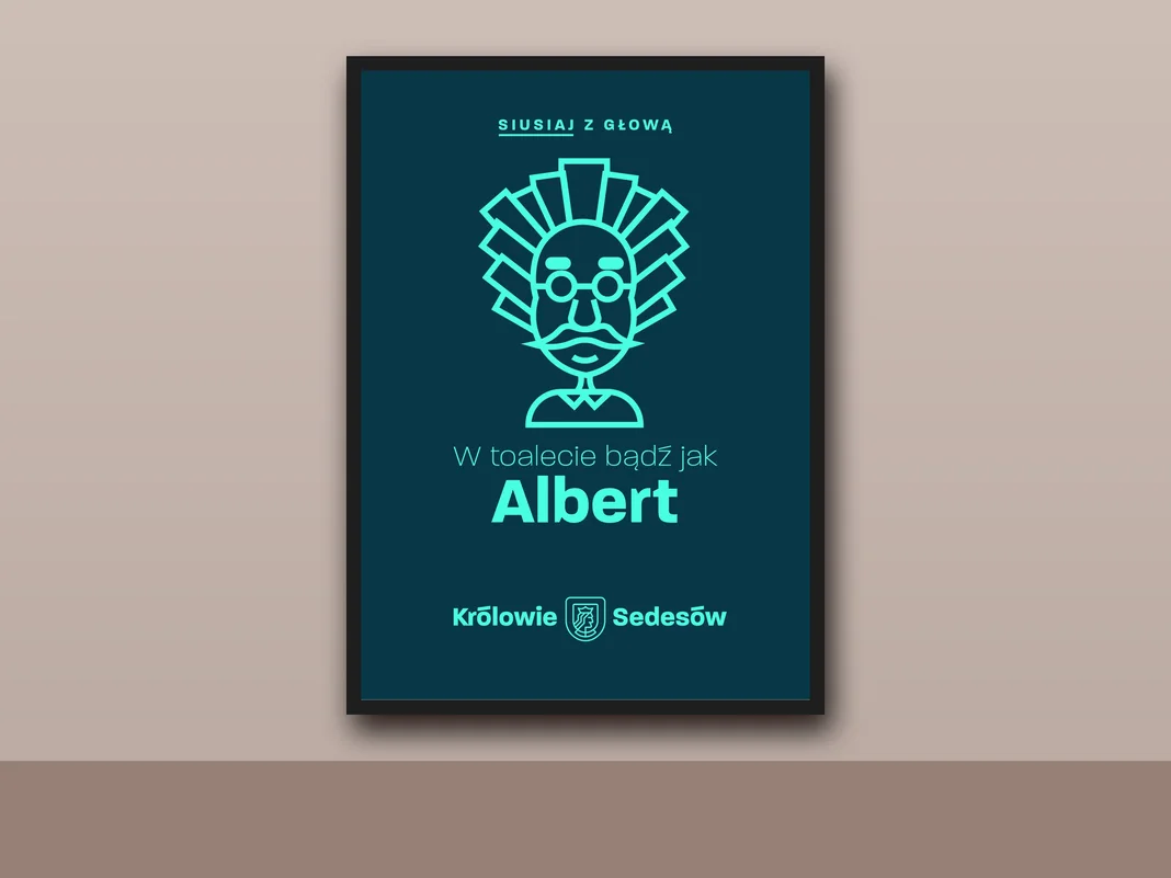 Plakat „W toalecie bądź jak Albert” w ramie na ścianie